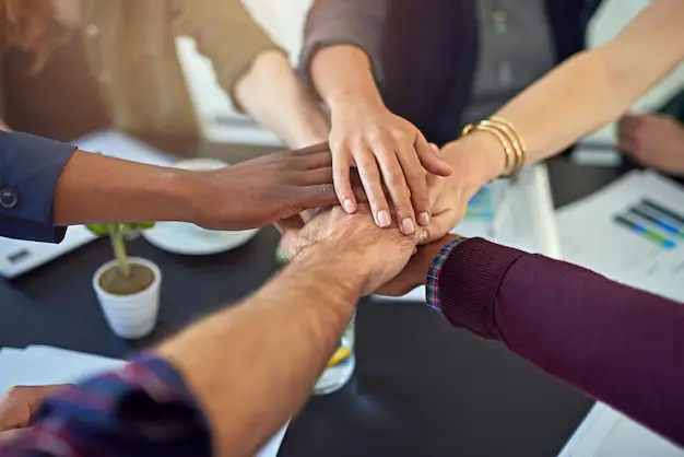 Equipo de trabajo uniendo las manos sobre una mesa